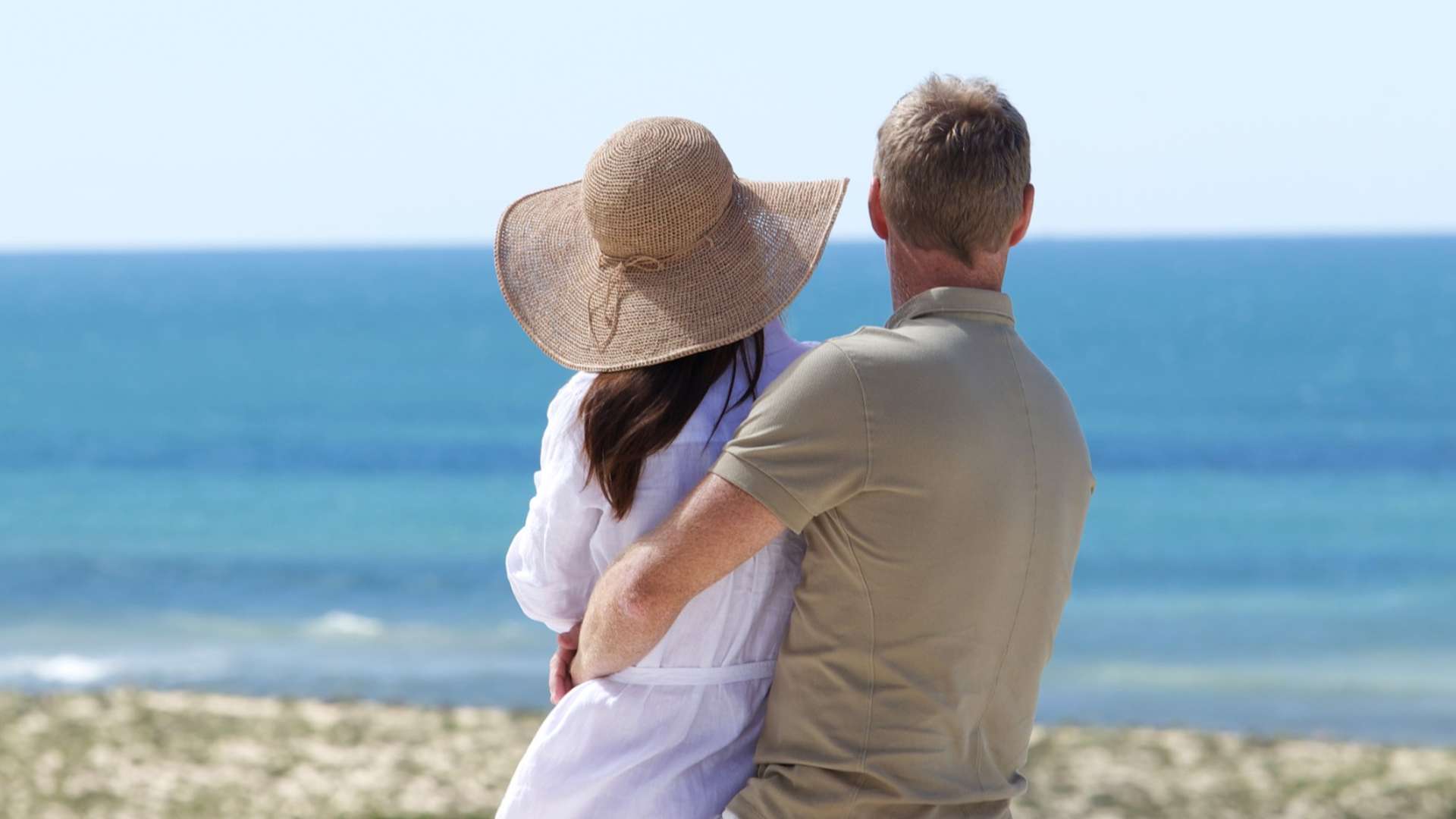 A couple standing on the beach, embracing while looking out over the ocean at Vale do Lobo Resort.
