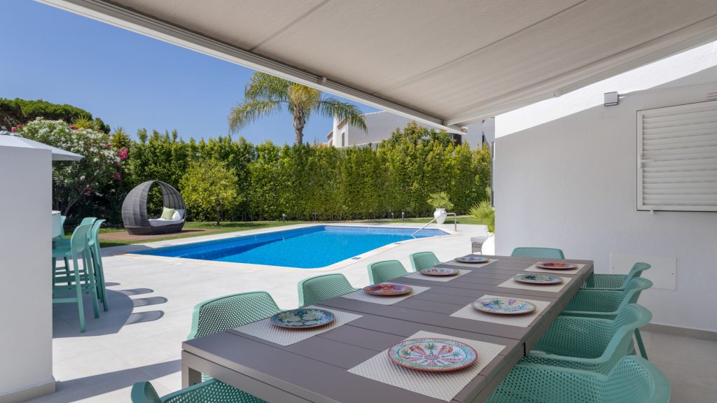 Outdoor dining table and barbecue area set on a sunny stone terrace