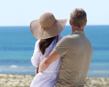 A couple standing on the beach, embracing while looking out over the ocean at Vale do Lobo Resort.